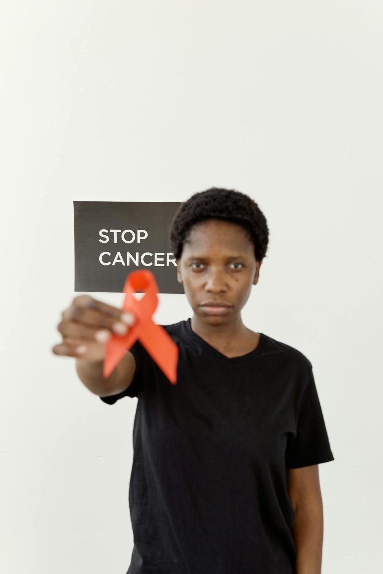 African American woman holding red ribbon to support cancer awareness.