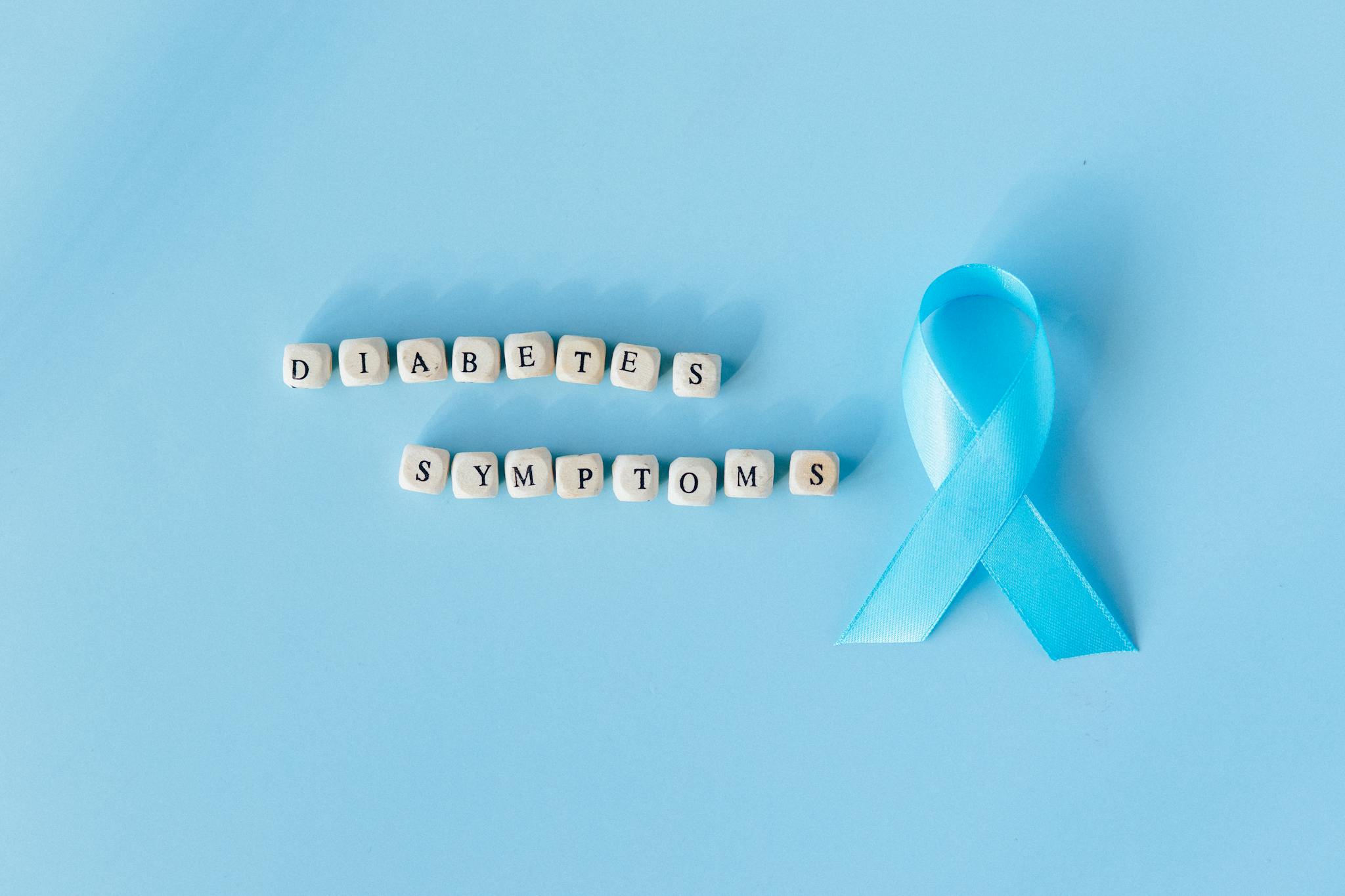 Conceptual image emphasizing diabetes symptoms with a blue awareness ribbon and letter dice.